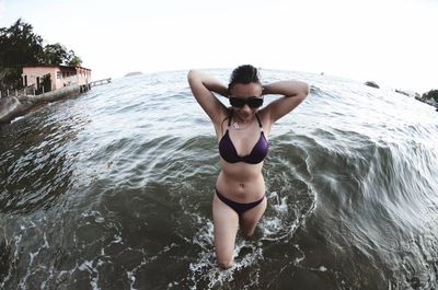 Sensuous woman wearing bikini in sea against clear sky