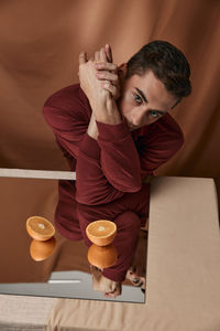 Portrait of man reflecting in mirror against colored background