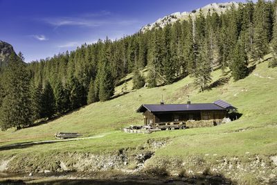 Alm hut on field against sky