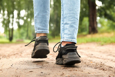 Fashion designer women's sneaker with high sole. female sports black shoe on forest background. 