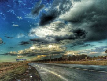 Road passing through landscape against cloudy sky