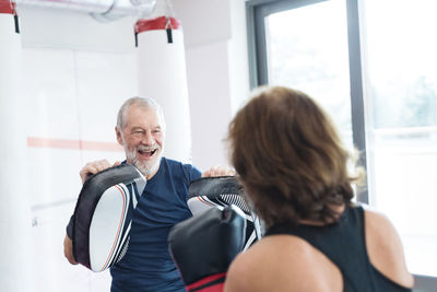 Fit senior woman boxing with her coach