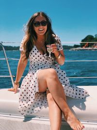 Portrait of smiling young woman sitting by sea