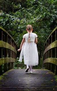 Rear view of girl in dress walking on footbridge