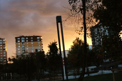 Silhouette trees and buildings against sky at sunset