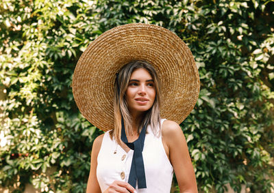 Portrait of smiling young woman standing against plants