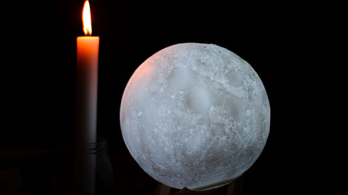 Close-up of burning candle against black background