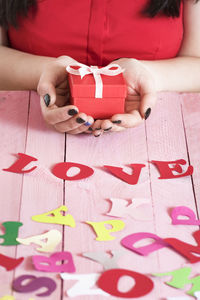 Midsection of woman holding gift with love text on table