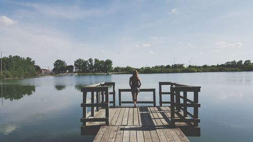 Rear view of woman on pier against lake