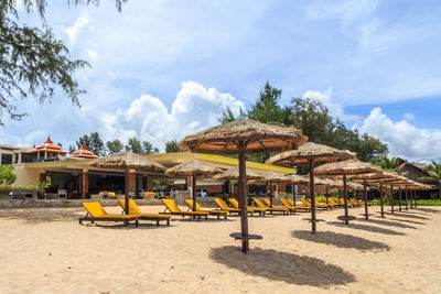 Deck chairs on beach against sky