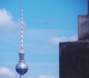 Communications tower by building against sky