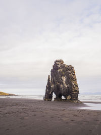 Rock formation on beach against sky