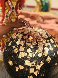 Merit making by sticking gold leaf on luknimit at thai temples