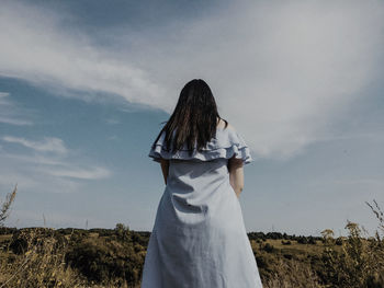 Rear view of woman standing on field against sky