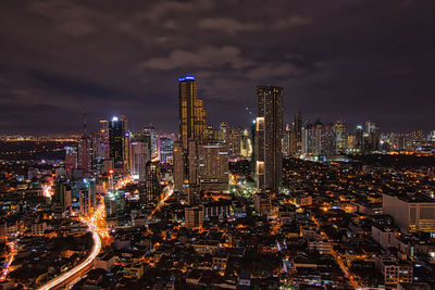 Illuminated modern buildings in city against sky at night