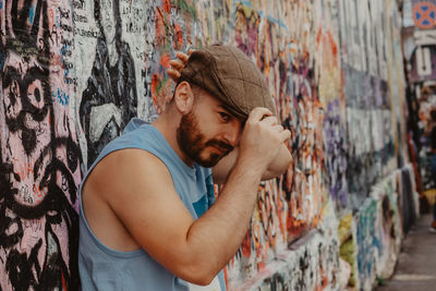 Side view of young man looking at graffiti wall