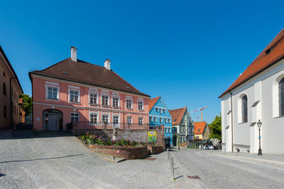 Street amidst buildings against blue sky