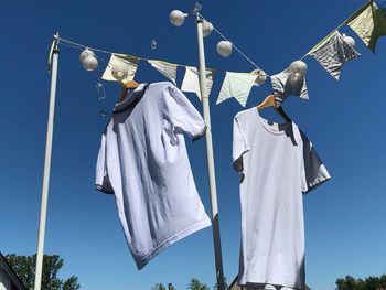 Low angle view of clothes hanging against blue sky