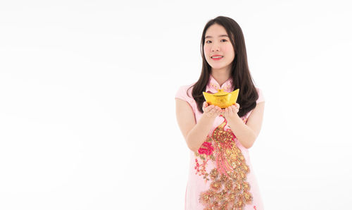 Portrait of smiling young woman standing against white background