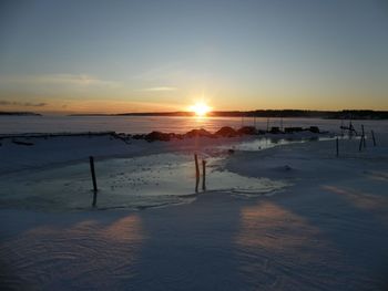 Scenic view of frozen beach against sky during sunset