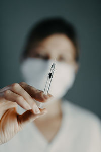 Doctor wearing protection face mask against coronavirus covid-19 with syringe in hand
