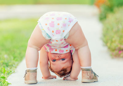 Portrait of cute baby girl with upside down standing on footpath