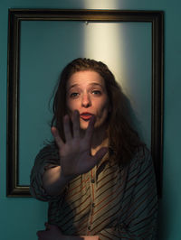 Mid adult woman standing against picture frame on wall