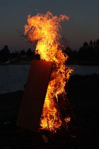 Bonfire on beach against orange sky