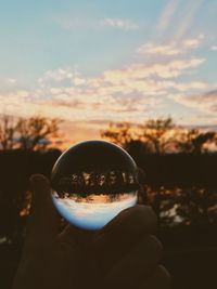 Man holding crystal ball with reflection of lake and trees in it