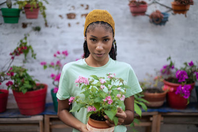 Portrait of woman standing by potted plant