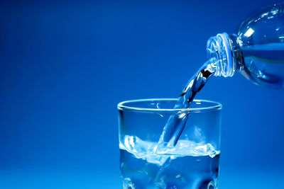 Close-up of drinking glass against blue background