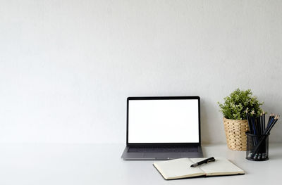 Low angle view of laptop on table against wall