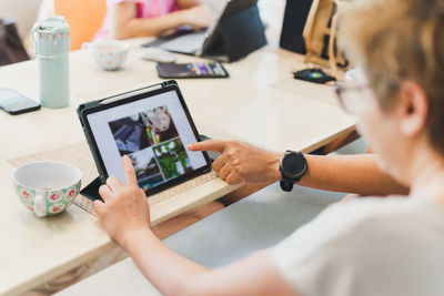 Midsection of boy using digital tablet while sitting on table