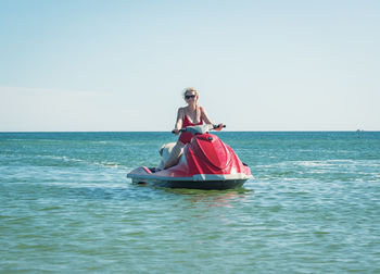 Rear view of woman swimming in sea against clear sky