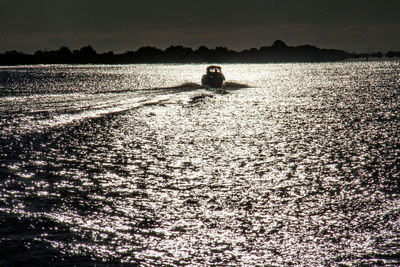 Silhouette man in boat on lake against sky during sunset