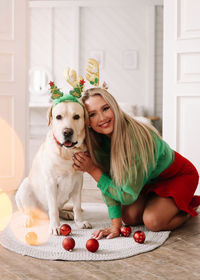 A beautiful smiling girl hugs a pet dog on a christmas holiday in the decorated interior of house