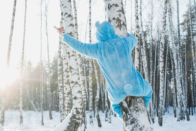 Woman with arms outstretched in forest during winter