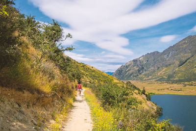 Rear view of woman walking on mountain against sky