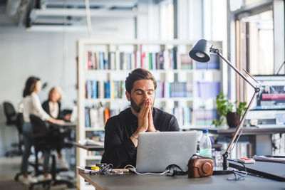 Worried businessman looking at laptop while sitting in office