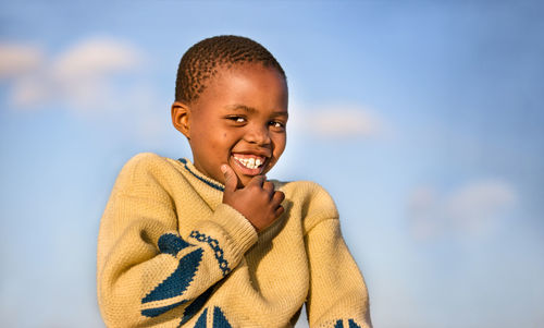 Close-up portrait of boy smiling against sky