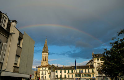 Low angle view of rainbow over buildings against sky