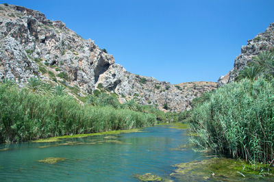 Scenic view of lake and mountains against clear blue sky