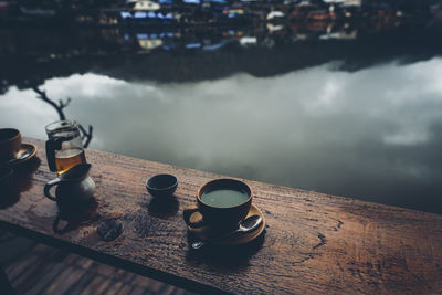 Coffee cup on table by lake
