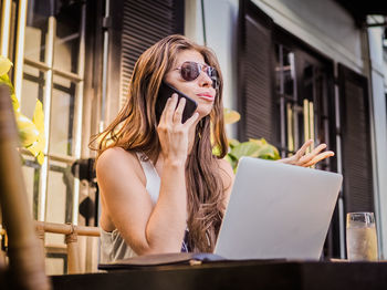 Young woman using phone while sitting on table