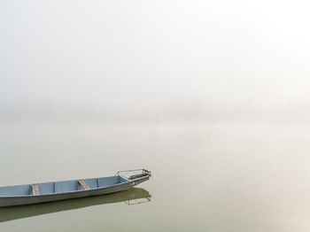 Boat moored on lake against fog