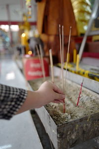 Close-up of hand holding incense in temple