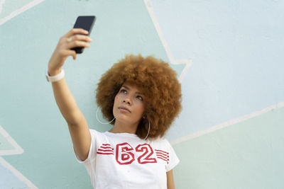 Woman with afro hair taking a selfie with her smartphone