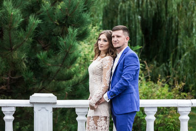 Young couple standing against trees