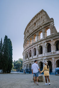 Rear view of couple by historical building against sky