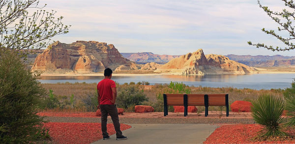 Rear view of man standing on mountain against sky